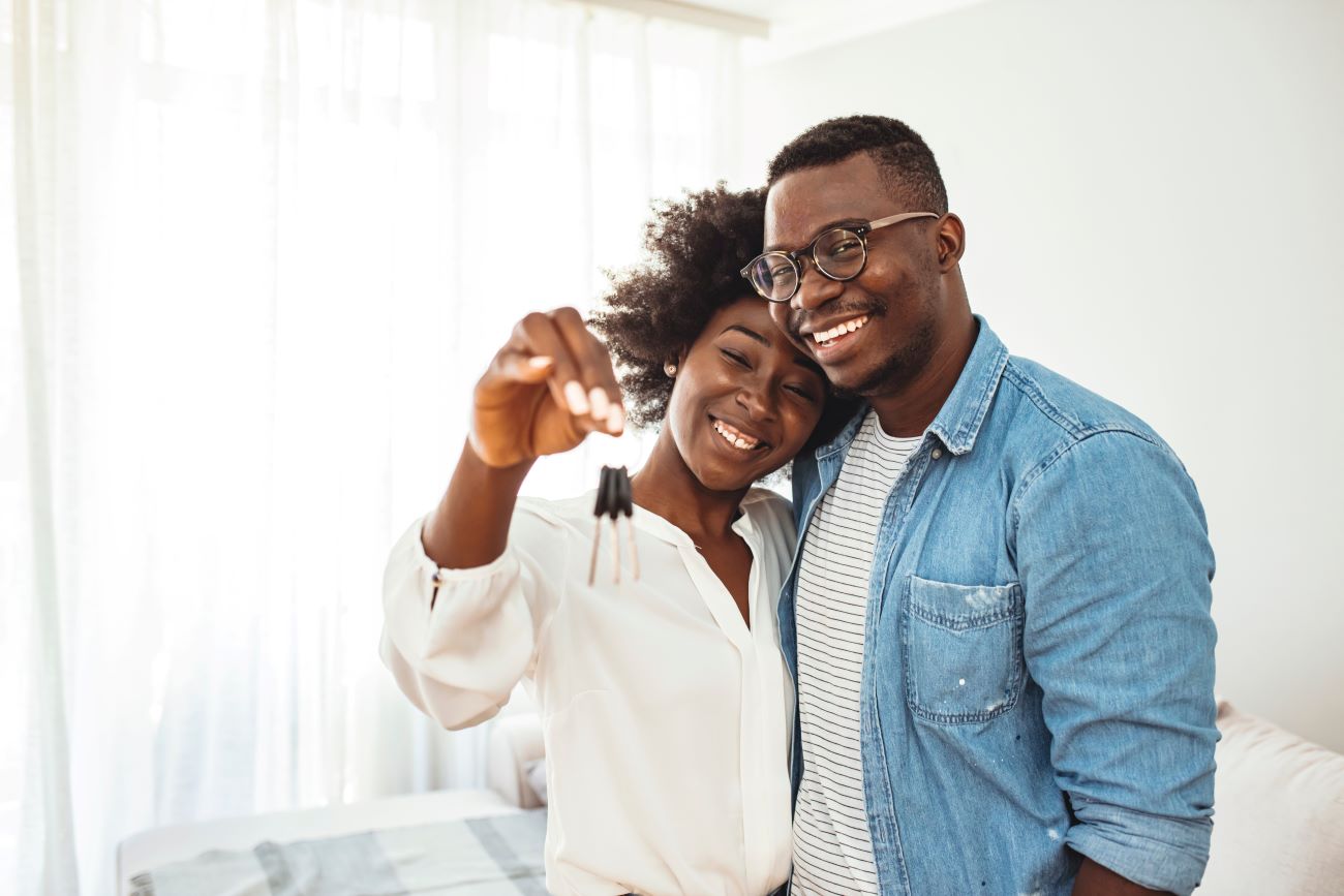 Smiling woman and man holding keys to new home they bought