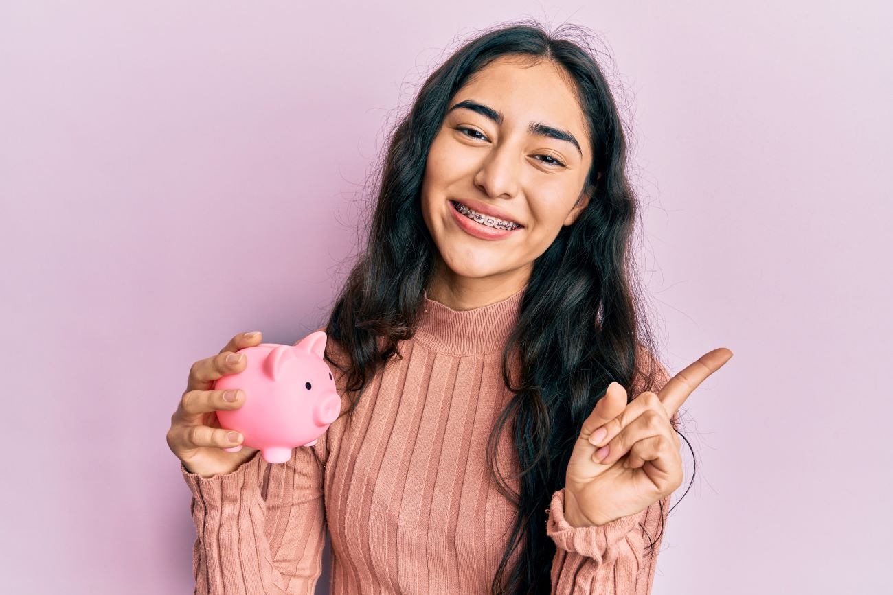 Smiling teenage girl holding piggy bank assessing investment risk