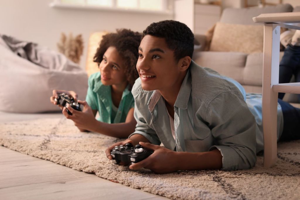 Two smiling teen boys play video game on screen