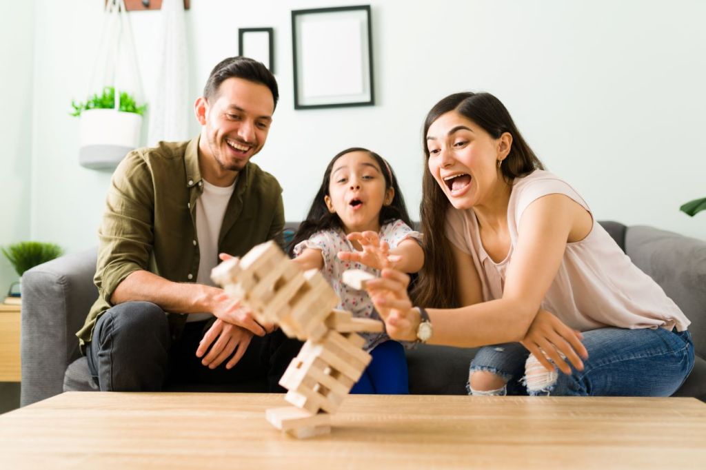 Family with man, girl, woman watch Jenga blocks fall