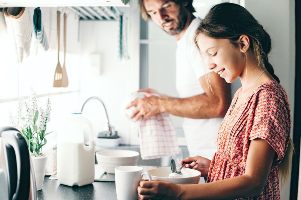 Man teaching teen girl to learn to cook