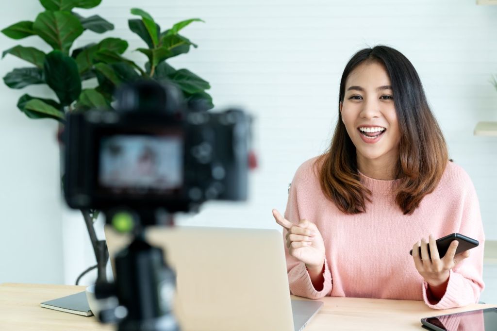 Asian woman smiling and talking to camera recording financial video for TikTok