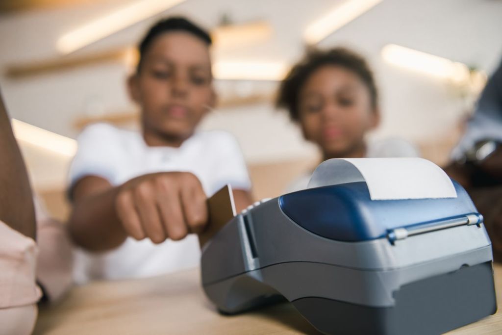 Boy and girl using debit card to pay for an item