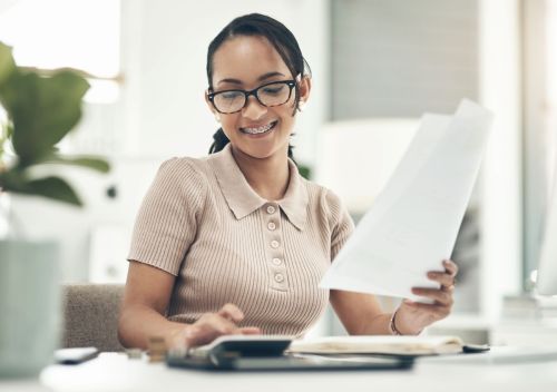 Teen girl holding pay stub and inputting numbers in calculator