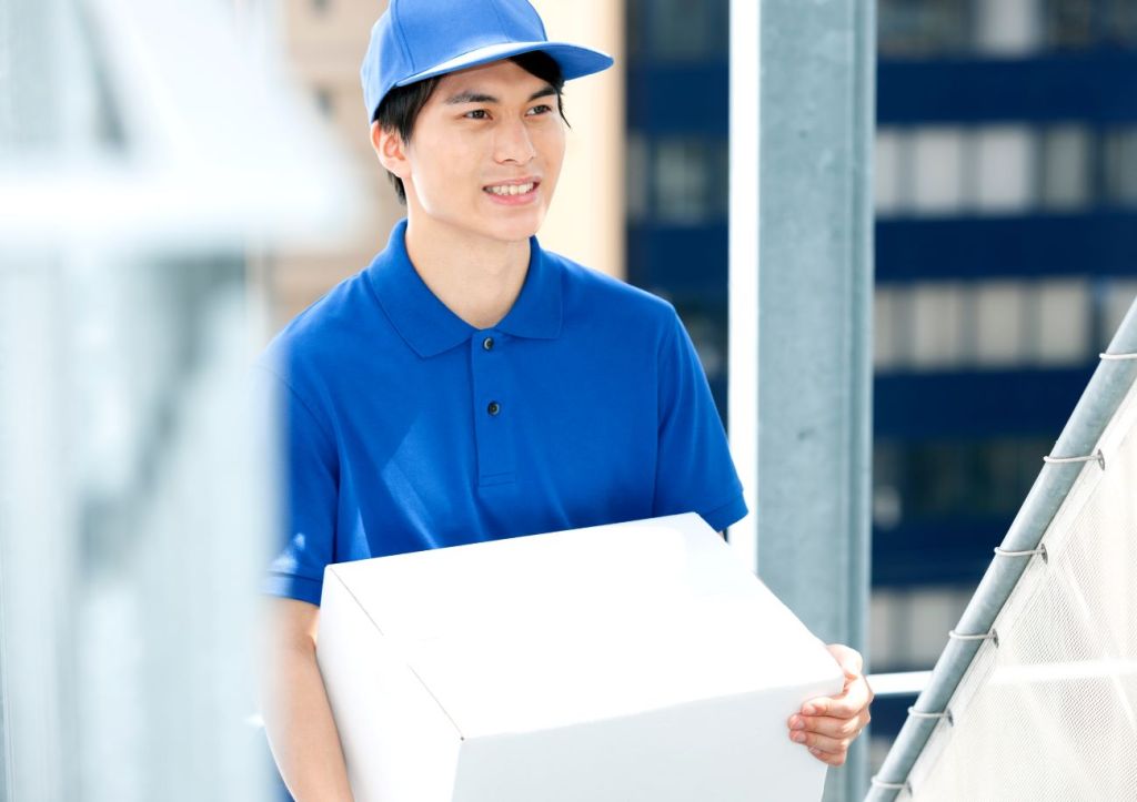 teen boy in blue shirt and cap working delivering a white box