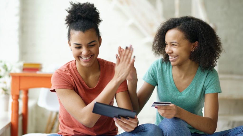 Two teen girls high fiving each other and smiling