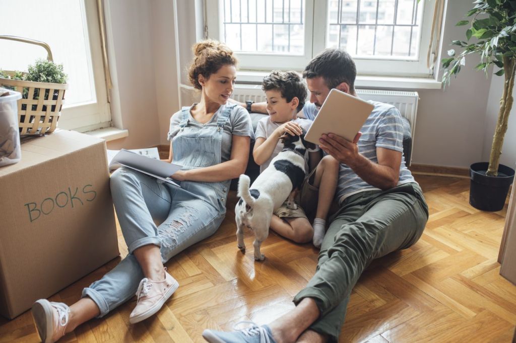 woman, boy, dog, and man sitting on floor of new house