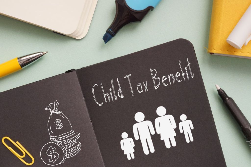 Book with stick figures of a family and title that reads Child Tax Benefit with stationery in the background