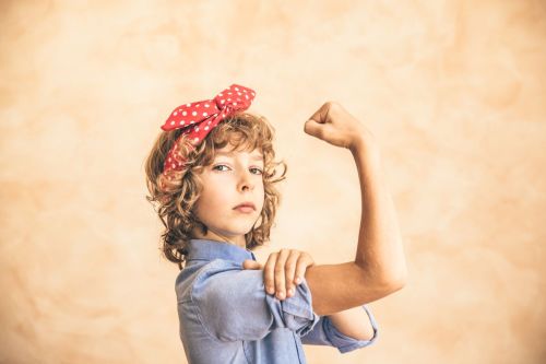 Image of teen girl with red hair ribbon and blue shirt posing like Rosie the Riveter