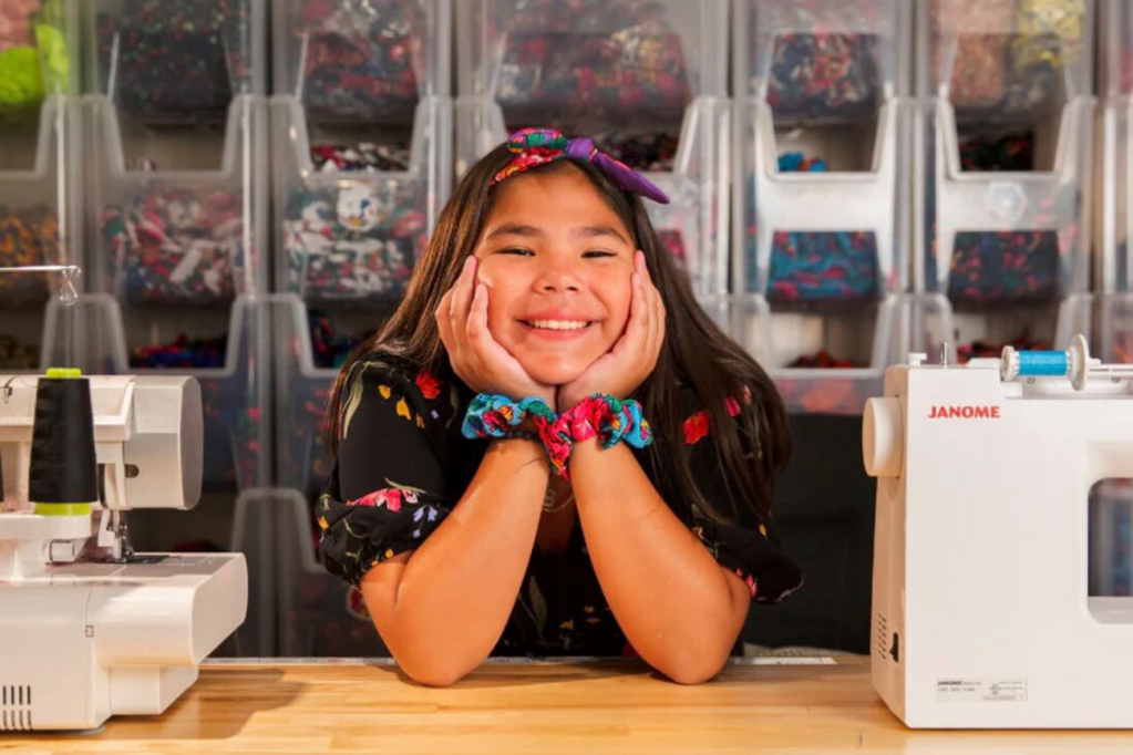 Image of Mya Beaudry, a teen girl with scrunchies around her wrists holding head in hands and smiling. 