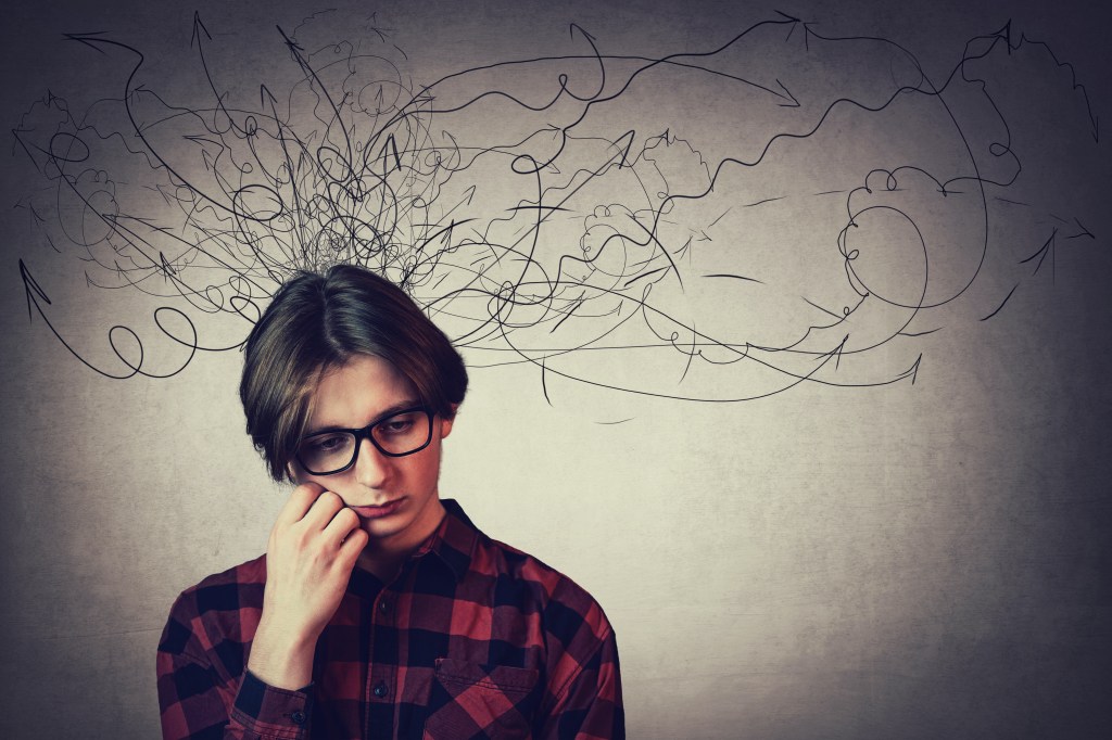 Closeup portrait of teen boy with his hand under cheek, with mess lines coming out of head.