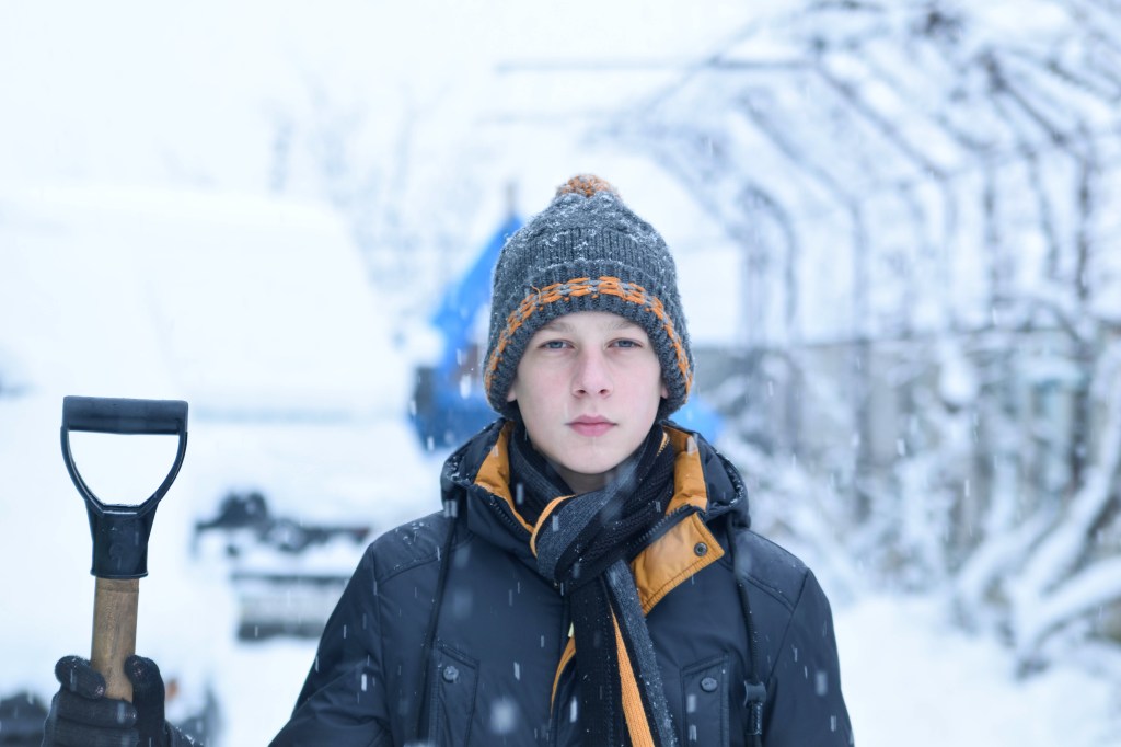 Teenager removing snow with a shovel in the winter