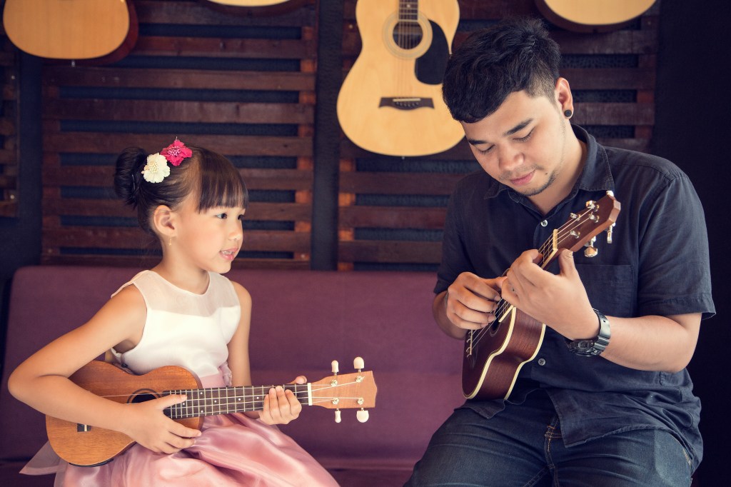 Teenager Ukulele Guitar teacher teaching girl music 