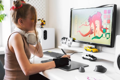 A young girl draws on a PC using a graphics tablet in her comfortable home office.