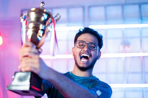 Smiling male professional gamer holding up trophy