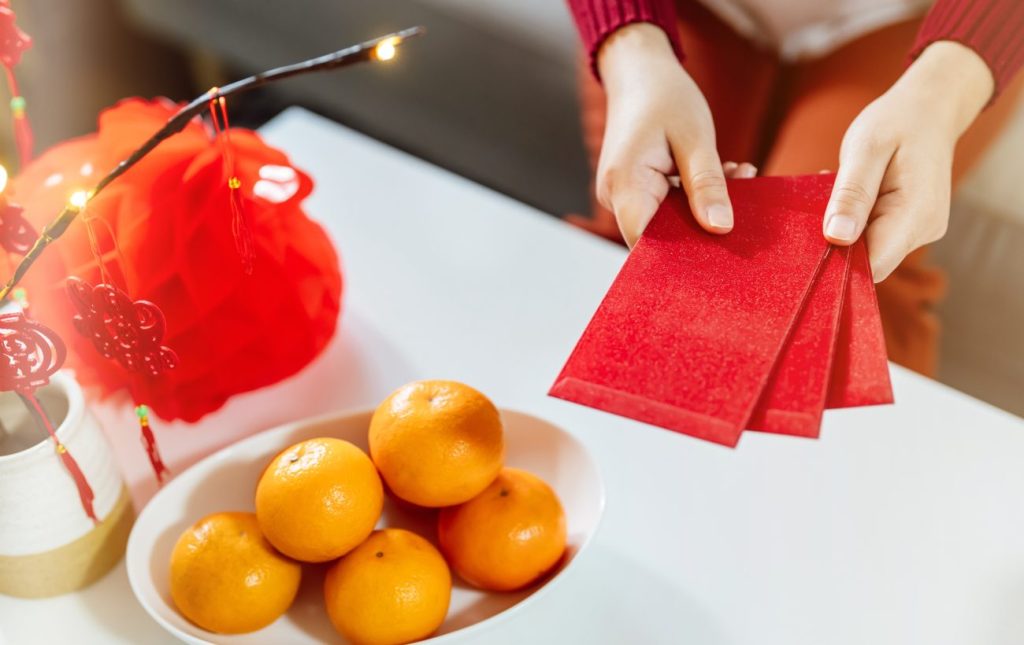 Lucky red envelopes and bowl of mandarines celebrating Lunar New Year