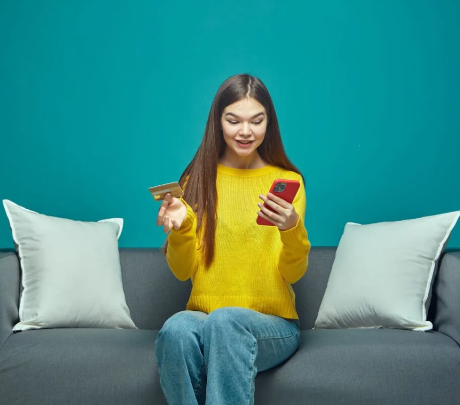Teen holding debit card and phone