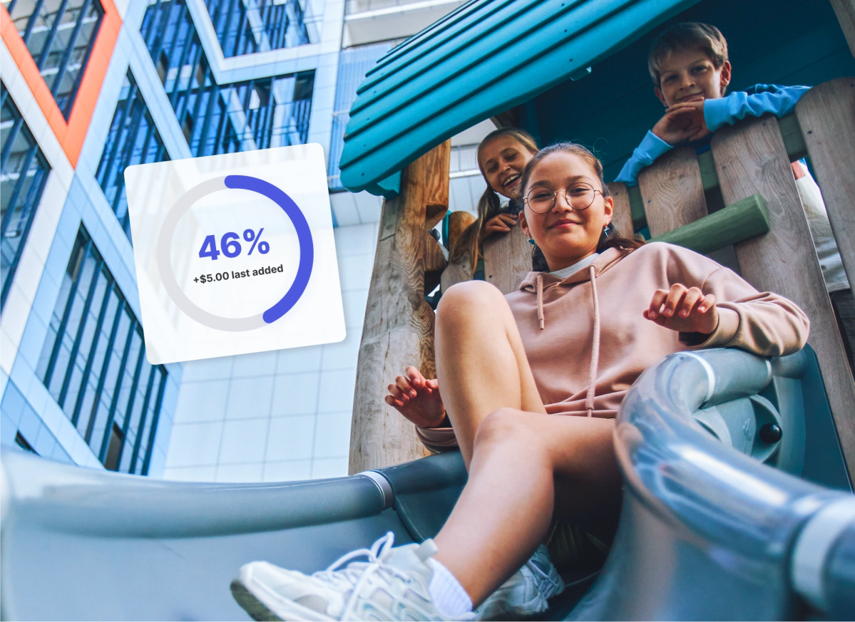 A child on a playground slide beside a savings progress ring, illustrating how kids grow with Mydoh and learn money and finance skills.