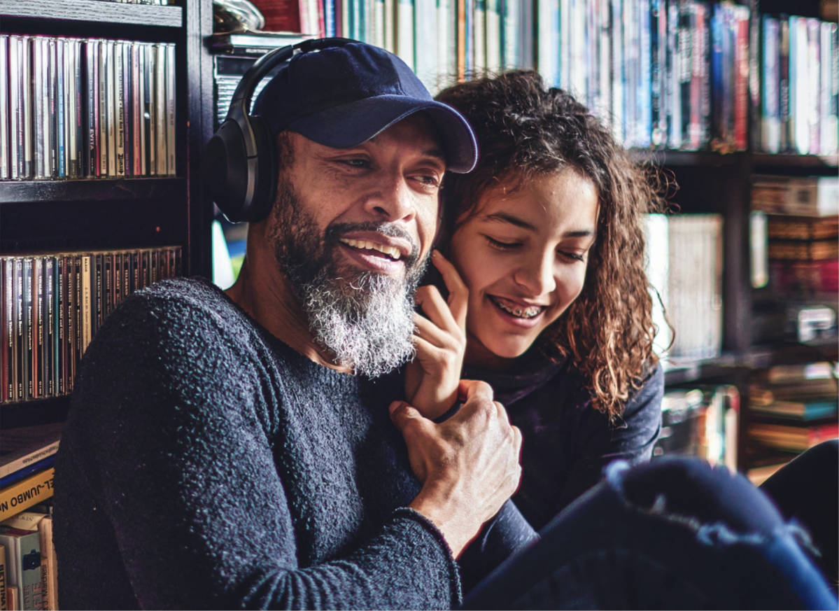 Two people smile together while looking down, sharing a warm moment that shows how it works to learn about money as a family.